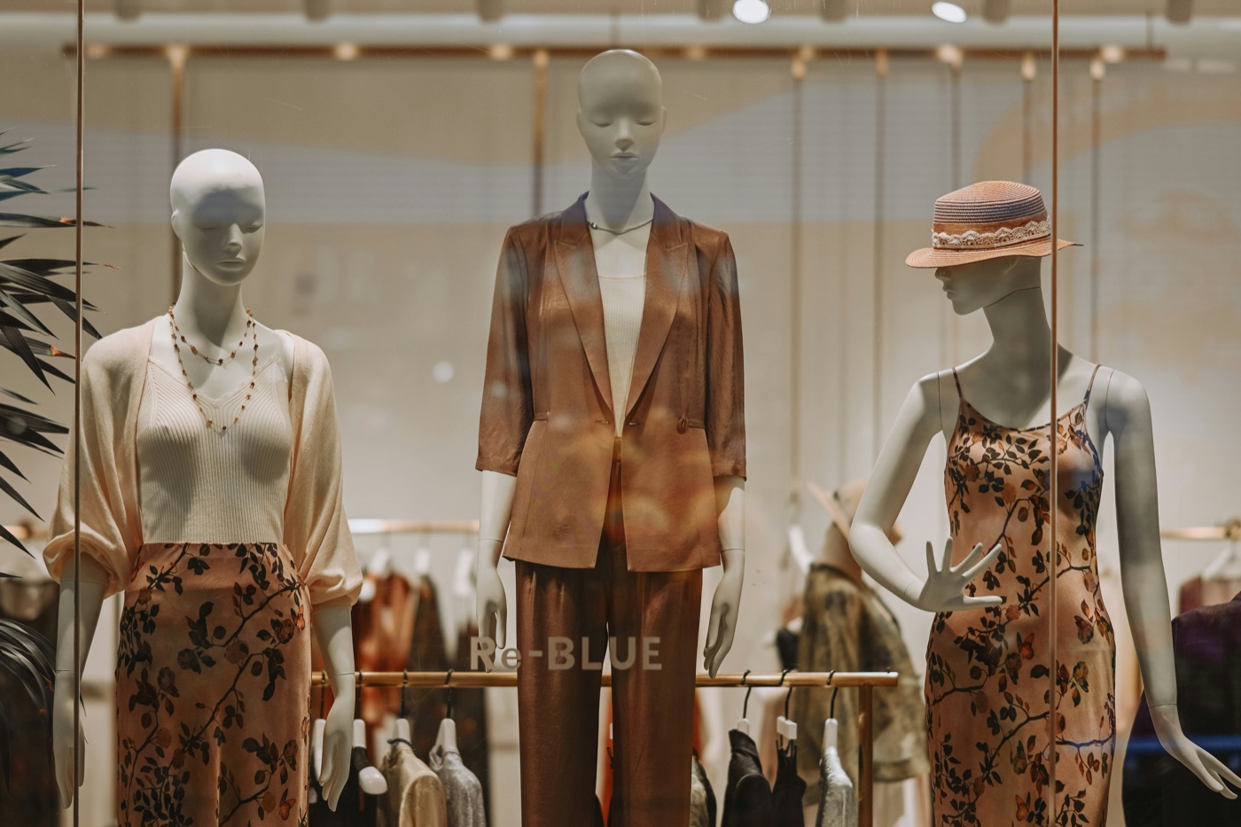 Boutique window display, three mannequins dressed in warm autumn tones.